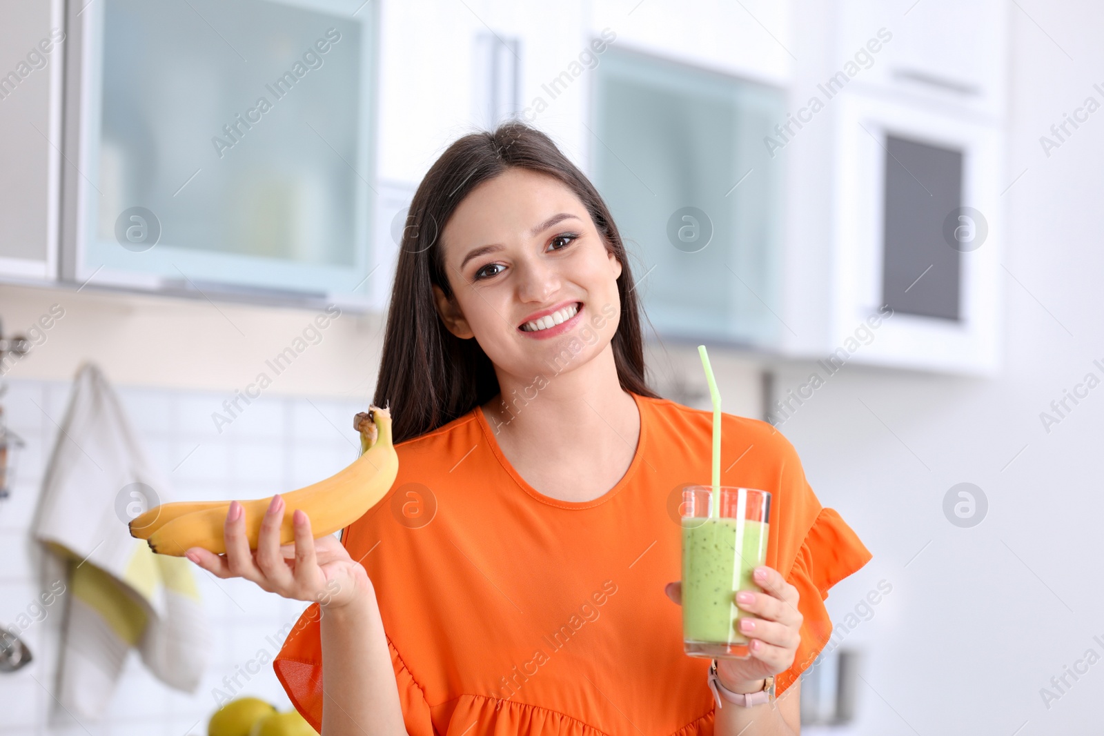 Photo of Young woman with glass of tasty healthy smoothie in kitchen