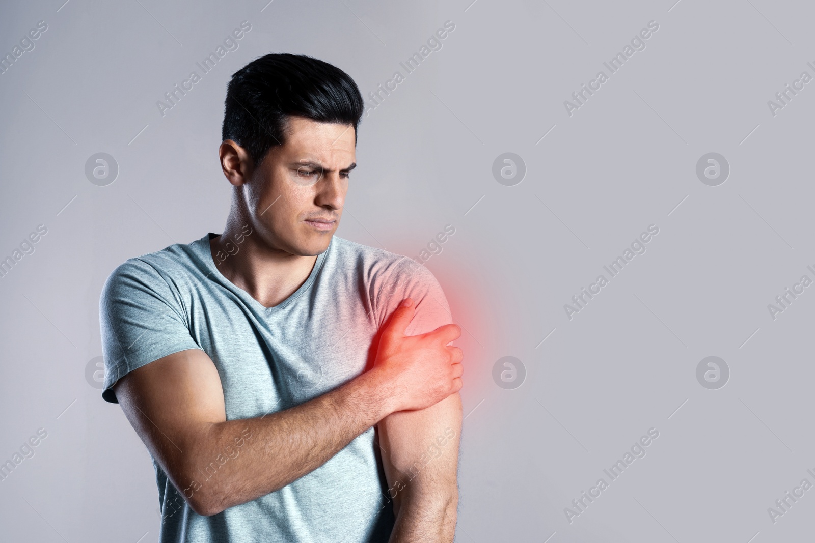 Image of Man suffering from shoulder pain on grey background. Space for text