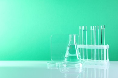 Photo of Laboratory analysis. Different glassware on table against green background, space for text