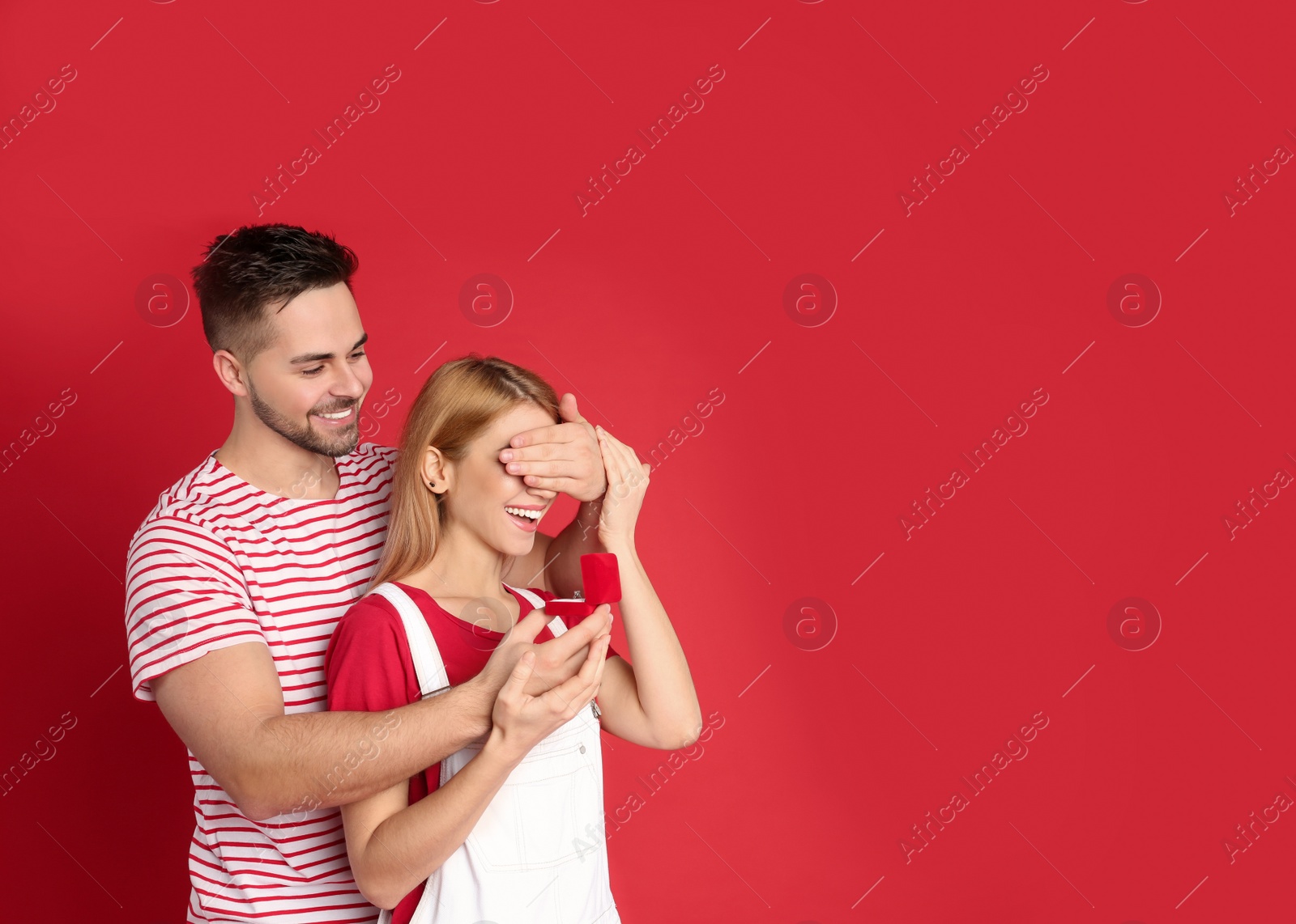 Photo of Man with engagement ring making marriage proposal to girlfriend on red background