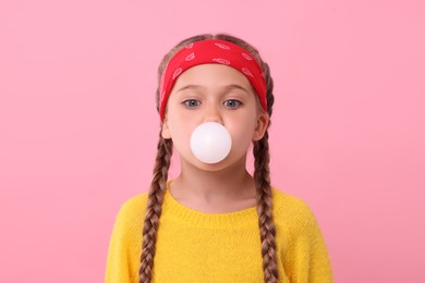 Photo of Girl blowing bubble gum on pink background
