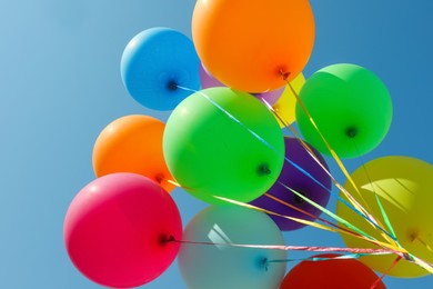 Photo of Bunch of colorful balloons against blue sky, bottom view