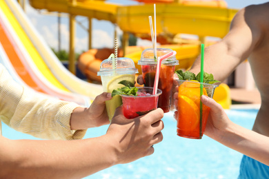 Photo of People with refreshing drinks in water park, closeup