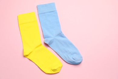 Photo of Colorful socks on light pink background, flat lay. Space for text