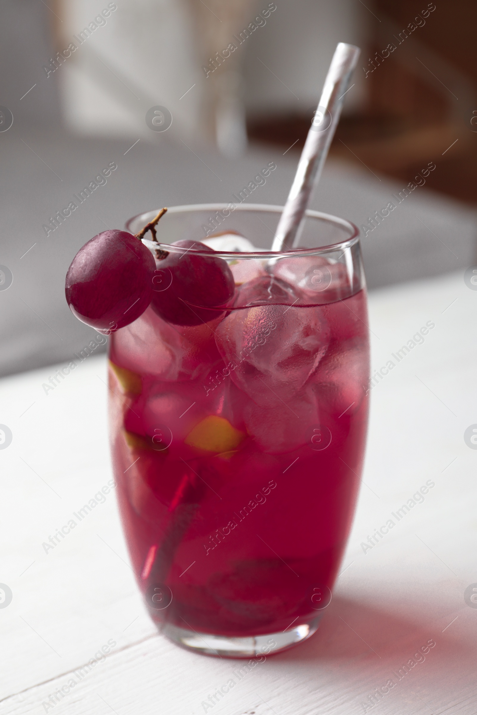 Photo of Grape soda water with ice and lime on white wooden table indoors. Refreshing drink