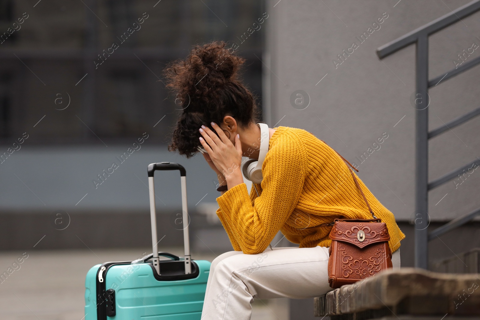 Photo of Being late. Frustrated woman with suitcase sitting on bench outdoors, space for text