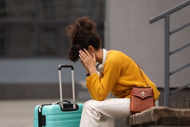 Photo of Being late. Frustrated woman with suitcase sitting on bench outdoors, space for text