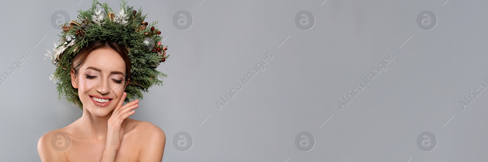 Image of Beautiful young woman wearing Christmas wreath on light grey background, space for text. Banner design 