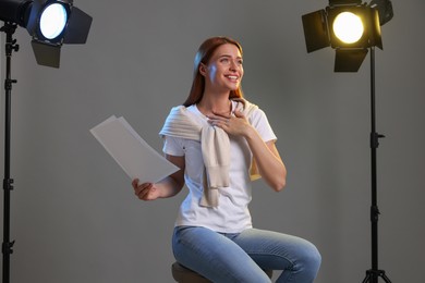 Photo of Casting call. Young woman with script performing on grey background in studio