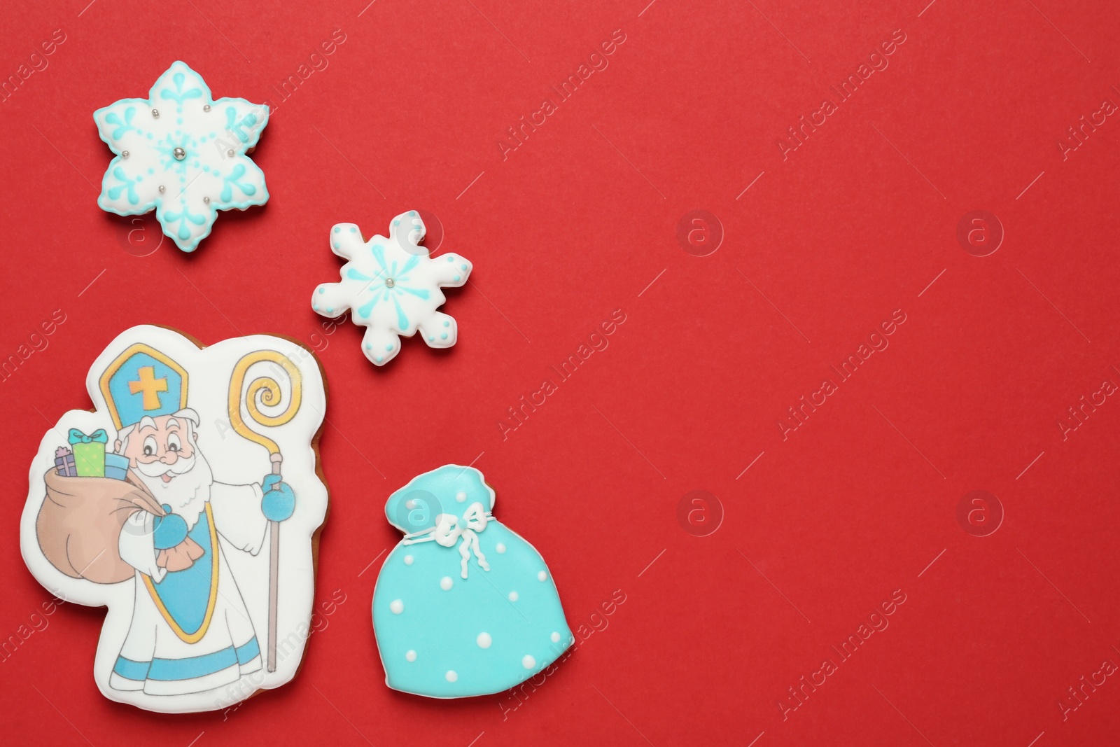 Photo of Tasty gingerbread cookies on red background, flat lay with space for text. St. Nicholas Day celebration
