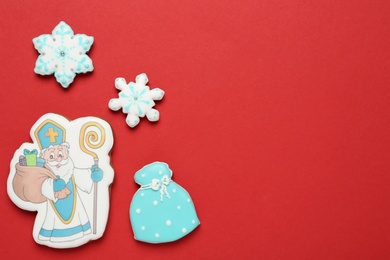 Tasty gingerbread cookies on red background, flat lay with space for text. St. Nicholas Day celebration