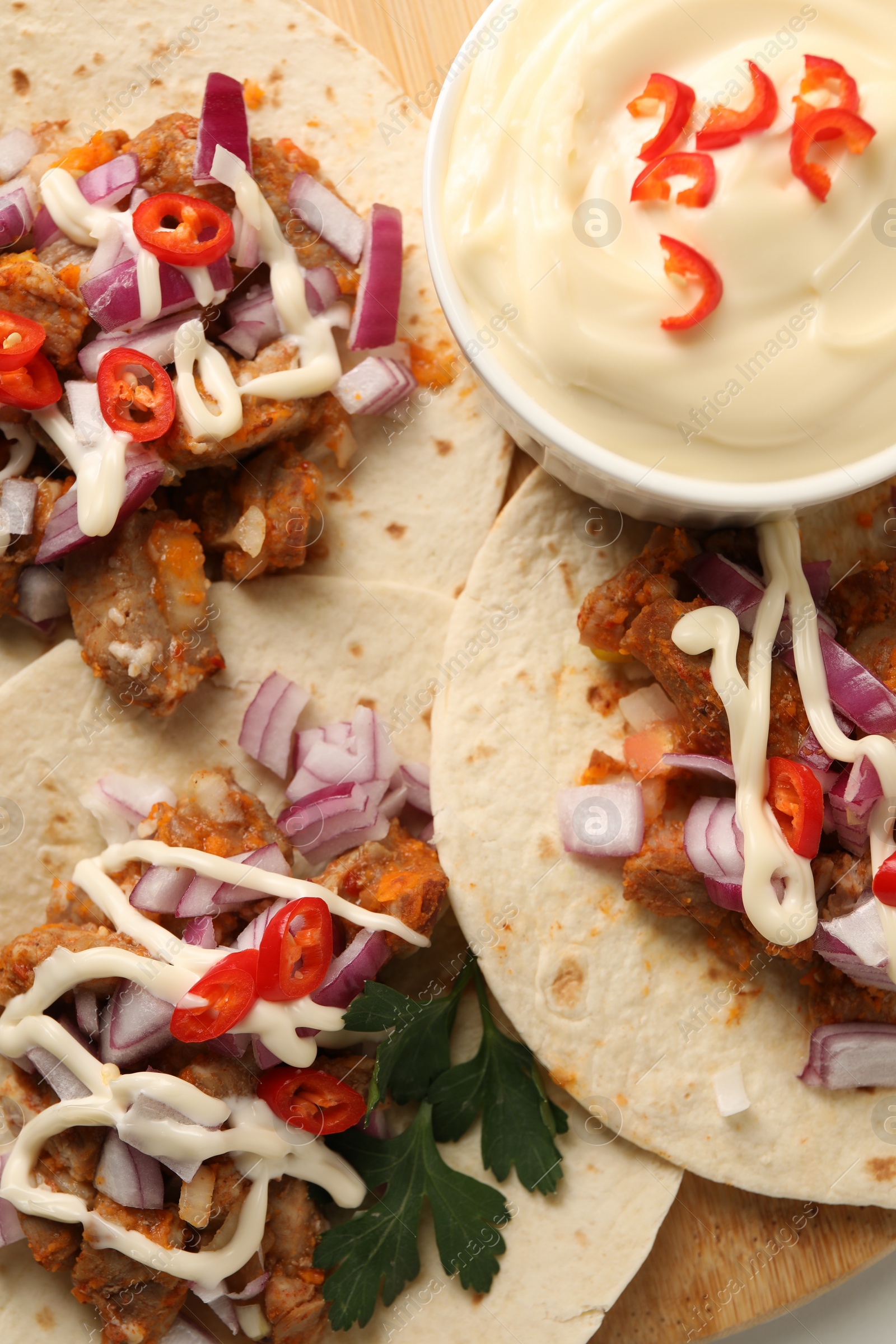 Photo of Delicious tacos with vegetables, meat and sauce on table, top view