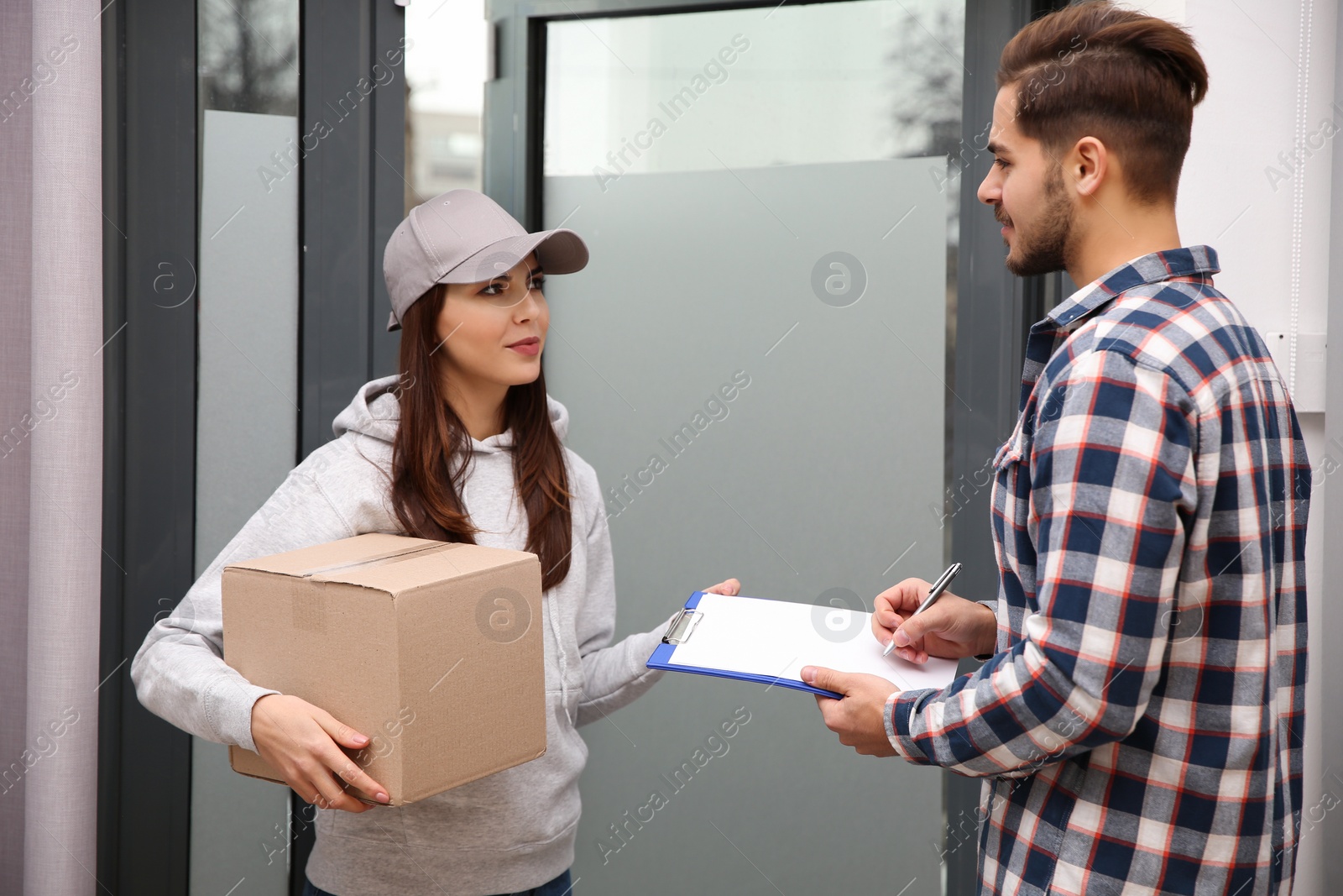 Photo of Man receiving parcel from delivery service courier indoors