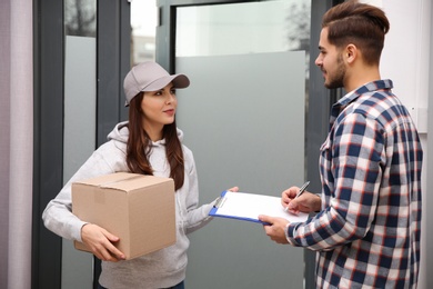 Man receiving parcel from delivery service courier indoors