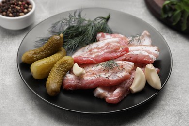 Tasty pork fatback with pickled cucumbers and spices on grey table, closeup