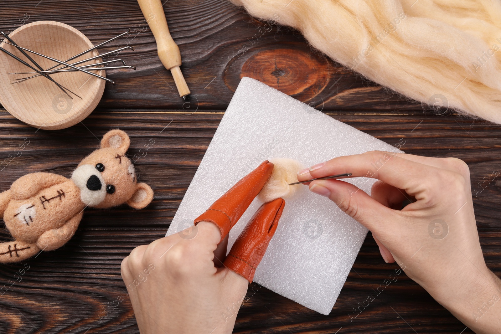 Photo of Woman felting from wool at wooden table, top view