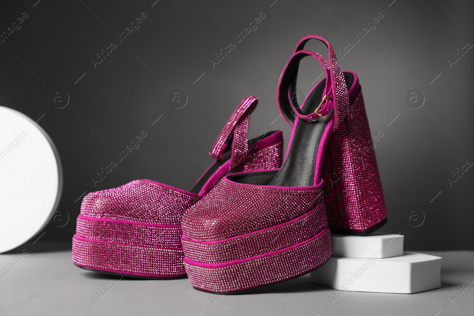 Photo of Fashionable punk square toe ankle strap pumps on light grey table. Shiny party platform high heeled shoes