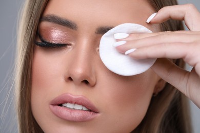 Beautiful woman removing makeup with cotton pad, closeup