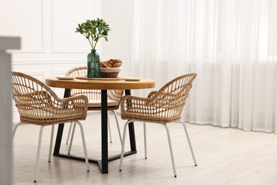 Photo of Dining room interior with comfortable furniture and green branches