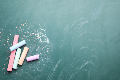 Pieces of color chalk on greenboard, flat lay. Space for text