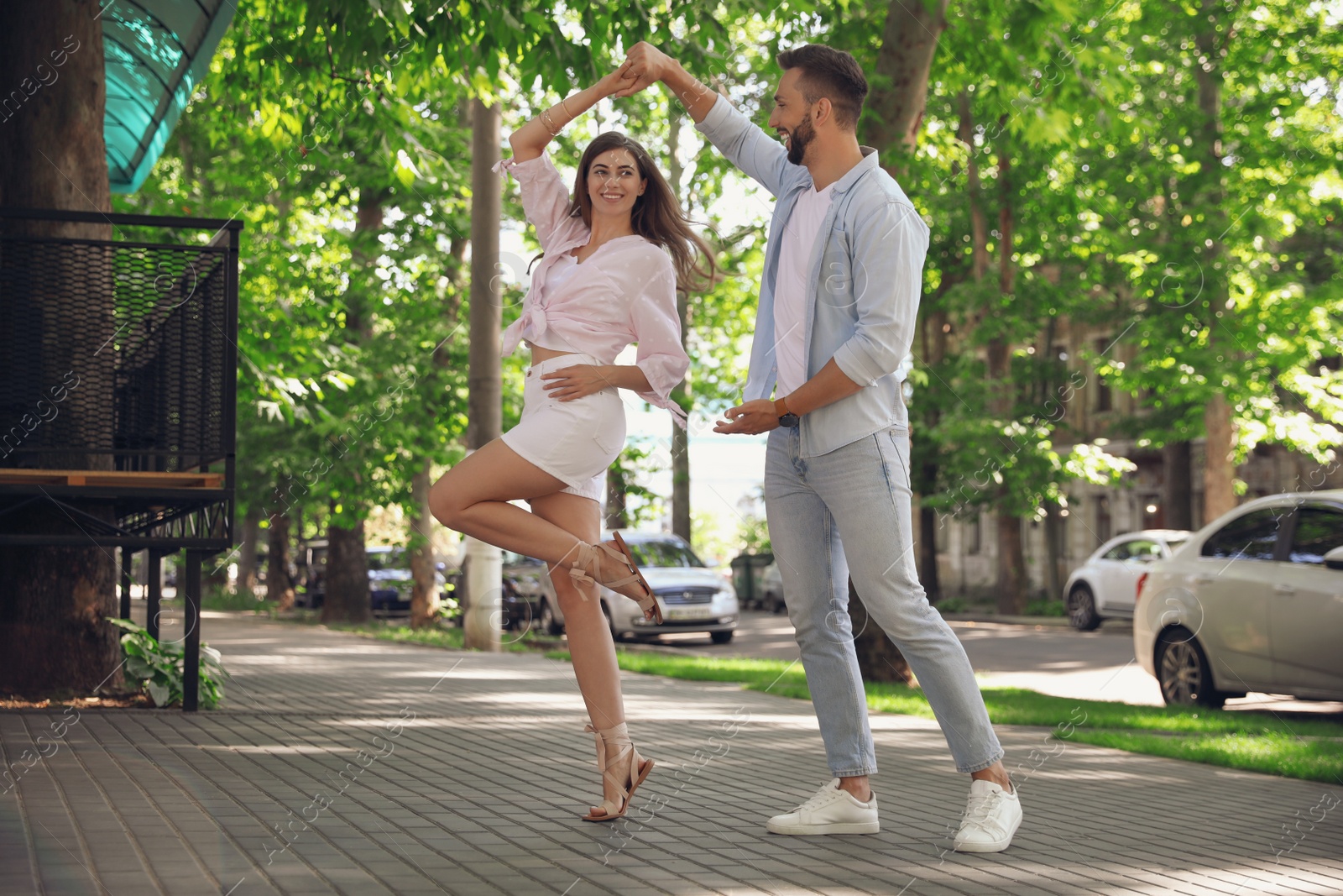 Photo of Lovely young couple dancing together outdoors on sunny day