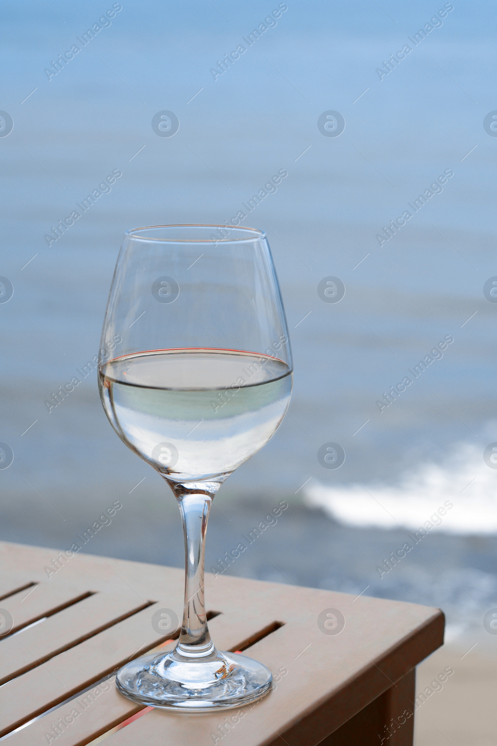 Photo of Glass with wine on table near sea