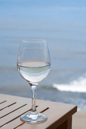 Glass with wine on table near sea