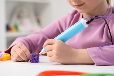 Photo of Girl drawing with stylish 3D pen at white table indoors, closeup