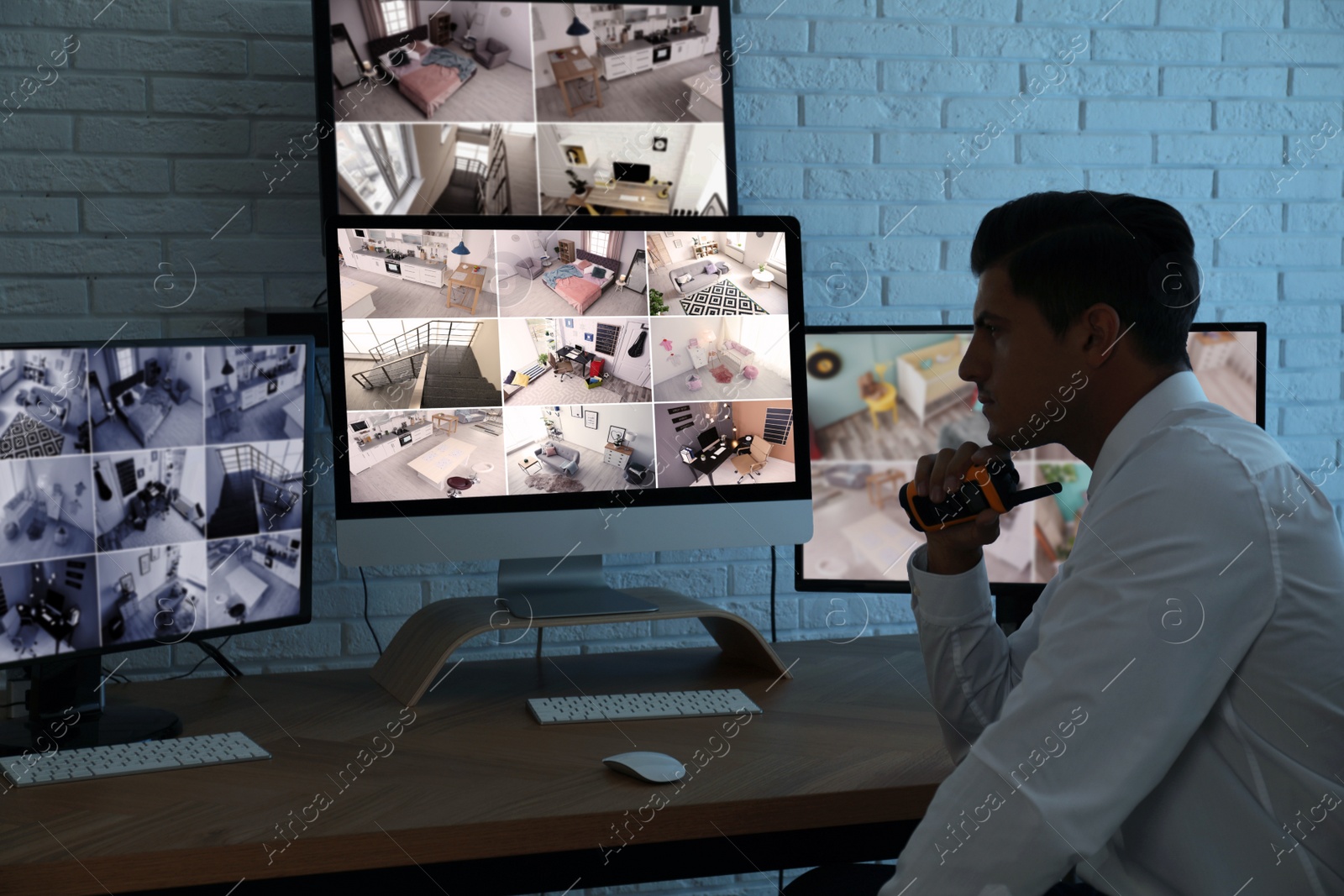 Photo of Male security guard with portable transmitter monitoring cameras at workplace