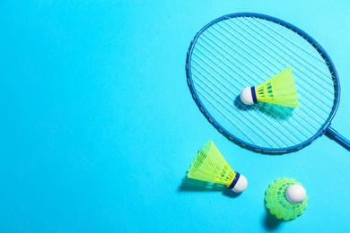 Photo of Badminton racket and shuttlecocks on light blue background, flat lay. Space for text