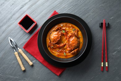 Photo of Delicious boiled crabs with sauce served on grey textured table, flat lay