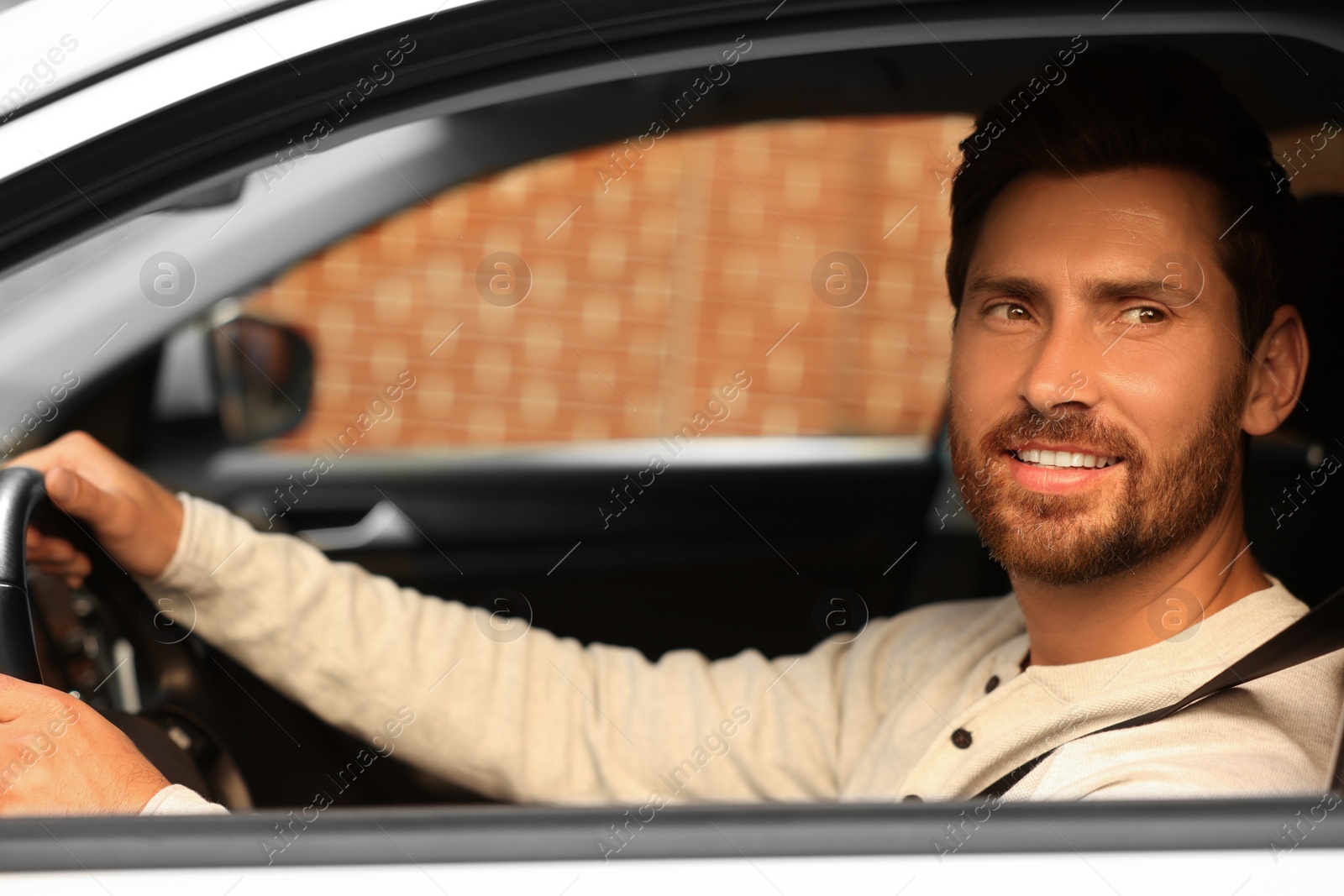 Photo of Enjoying trip. Handsome bearded man driving his car, view from outside