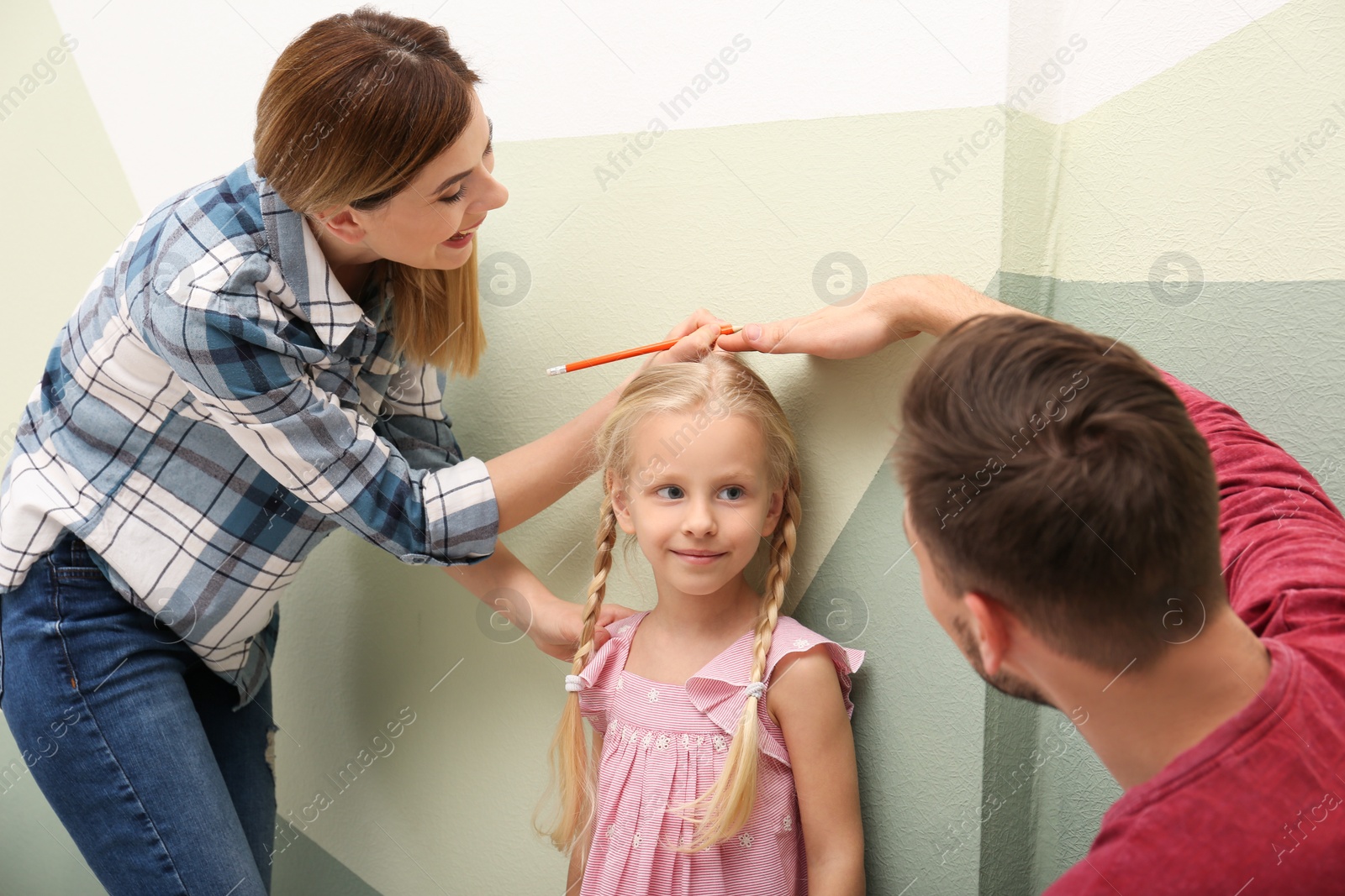 Photo of Parents measuring their daughter's height at home