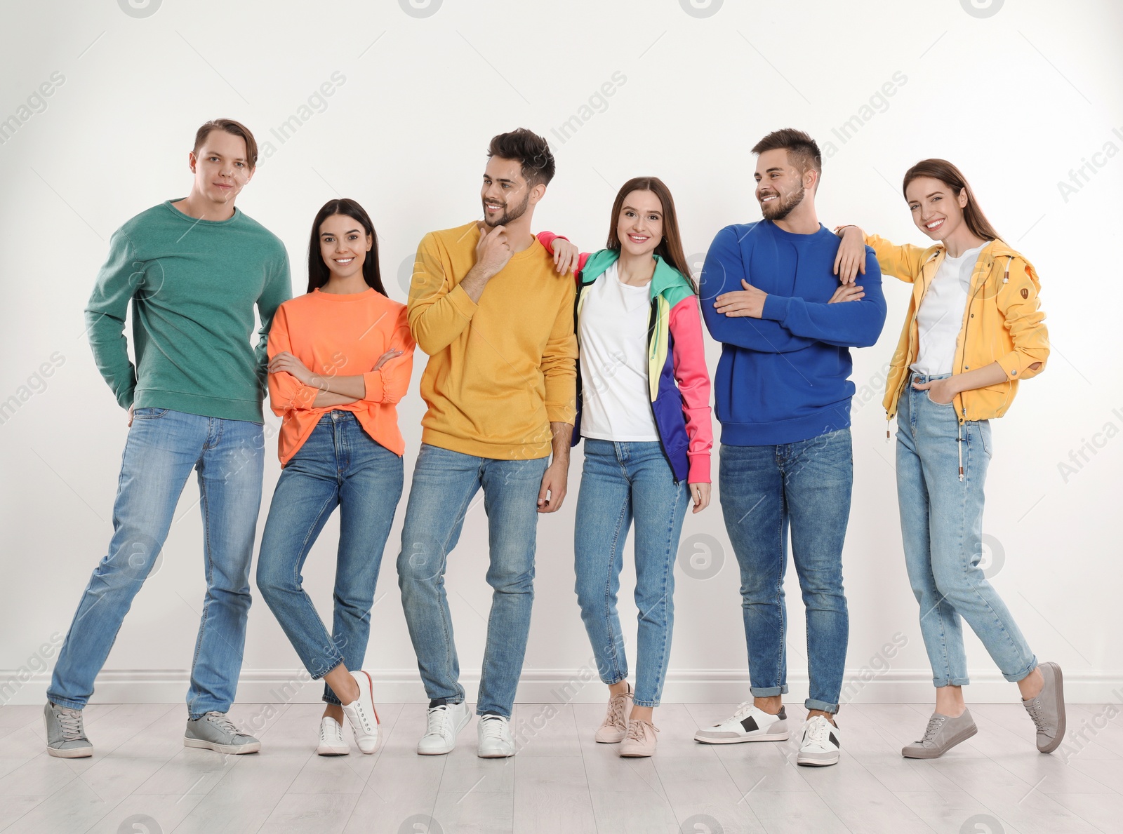 Photo of Group of young people in stylish jeans near white wall
