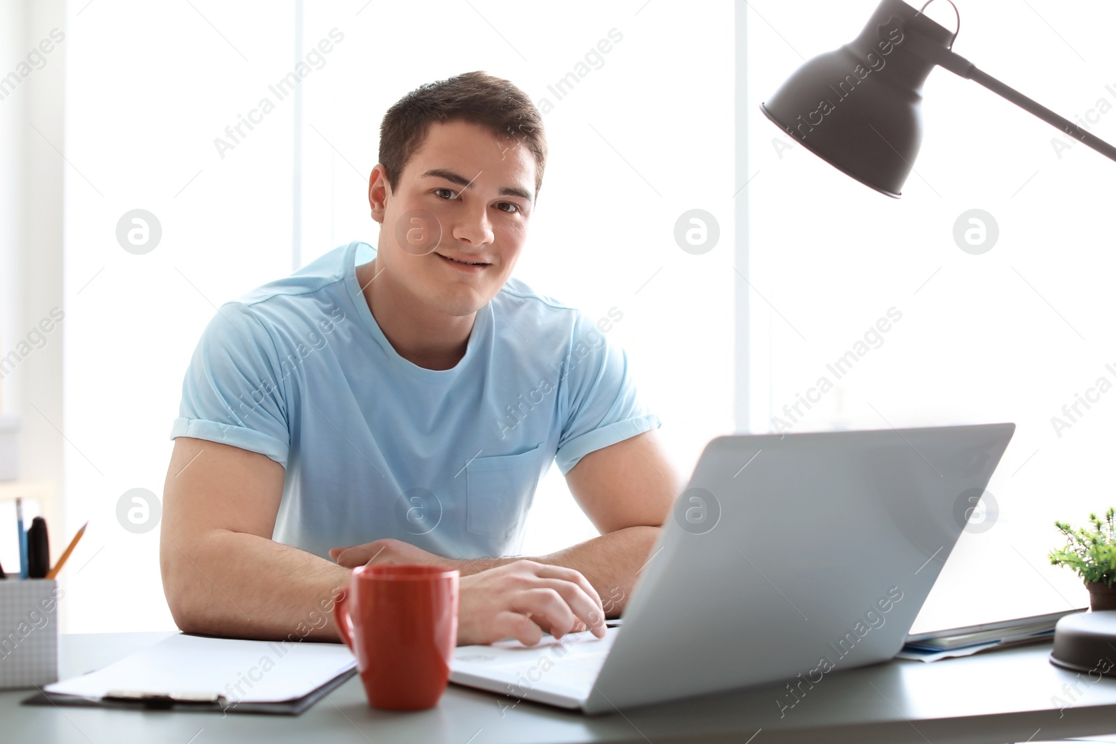 Photo of Portrait of confident young man with  laptop at table