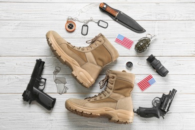 Set of military equipment and combat boots on wooden background, flat lay