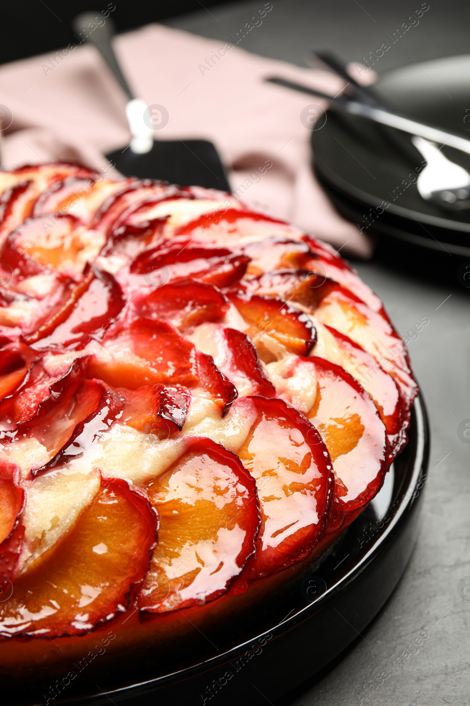 Photo of Delicious cake with plums on grey table, closeup