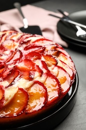 Photo of Delicious cake with plums on grey table, closeup