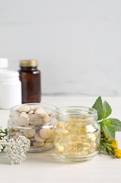 Photo of Jars with different pills, flowers and herbs on white wooden table, space for text. Dietary supplements