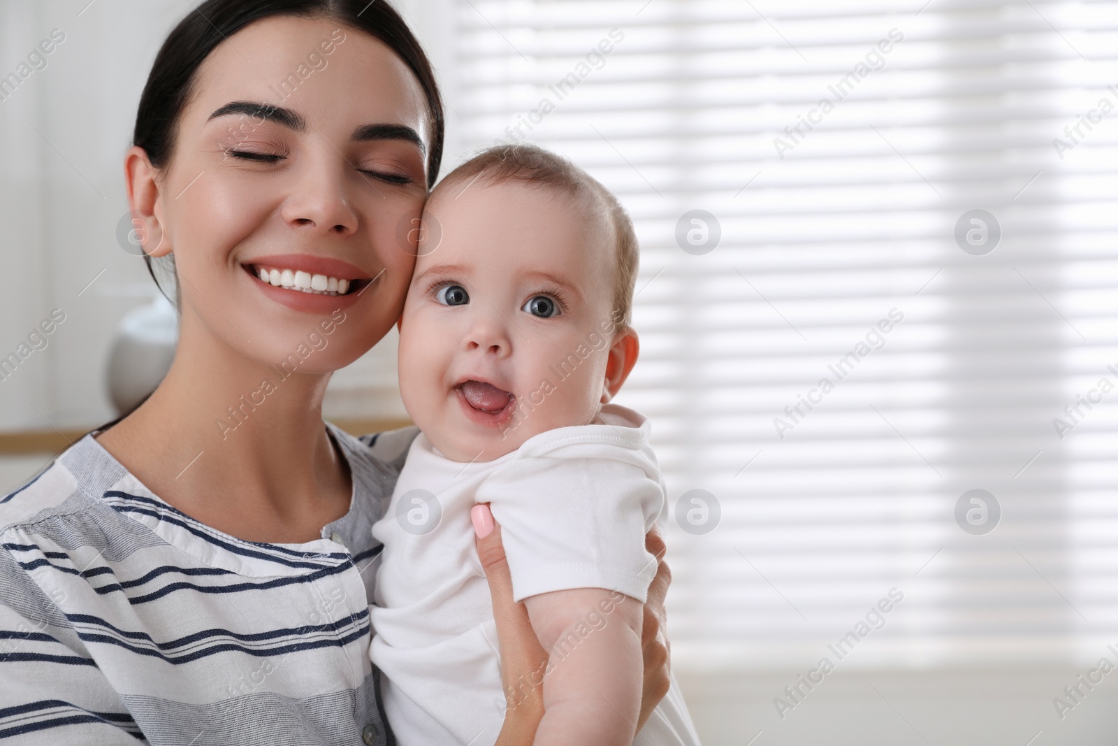 Photo of Young mother with her little baby at home, space for text