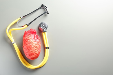 Photo of Stethoscope and model of heart on gray background. Heart attack concept