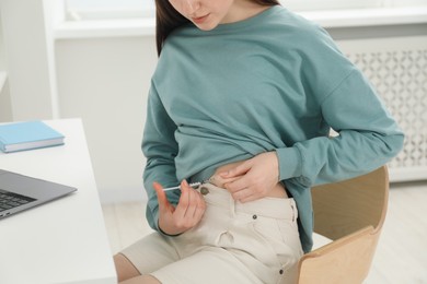 Photo of Diabetes. Woman making insulin injection into her belly at table indoors, closeup