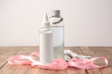 Photo of Composition with makeup removers and false eyelashes on wooden table against white background