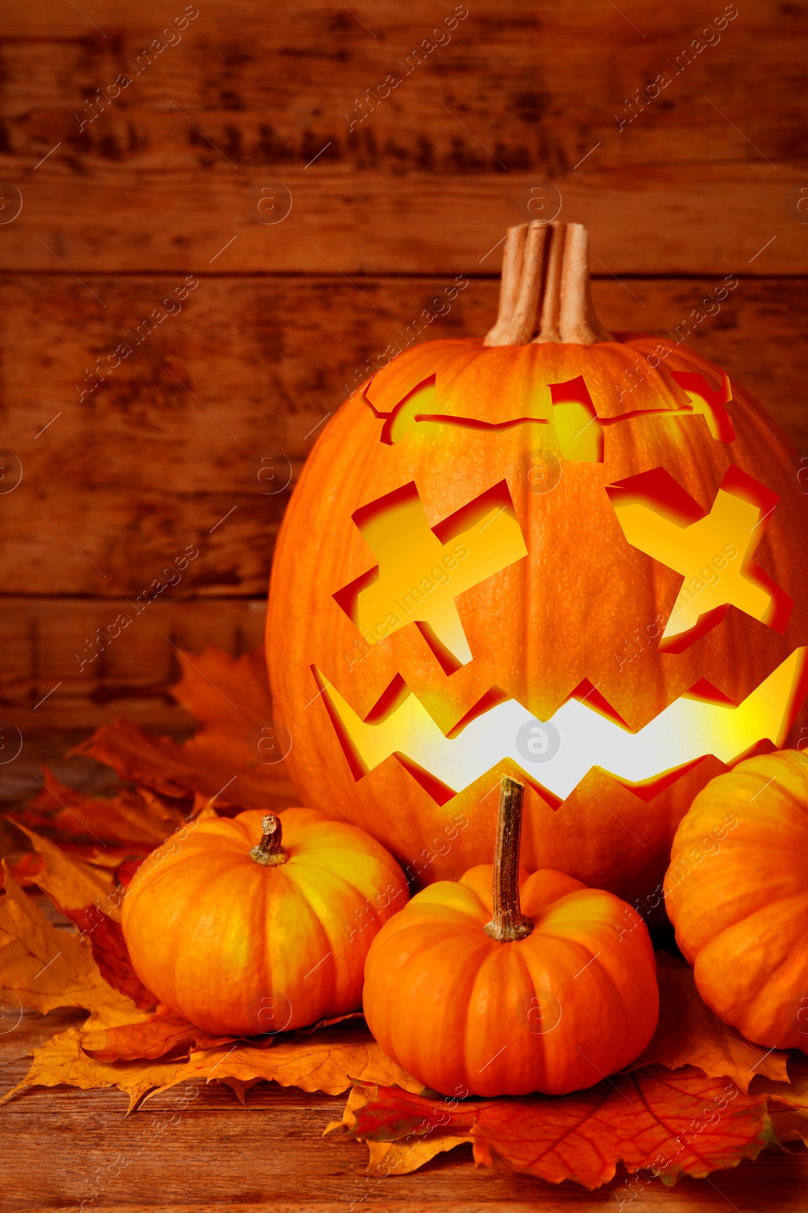 Image of Spooky jack o`lantern and dry autumn leaves on wooden table. Halloween decor