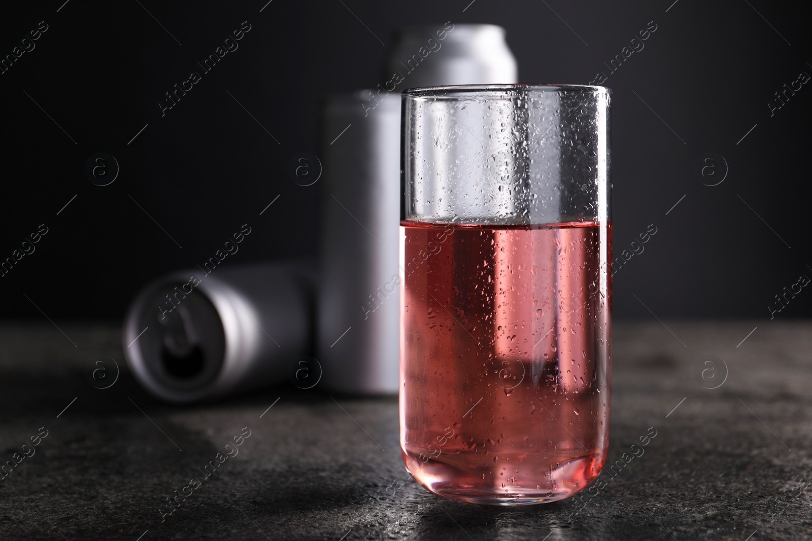 Photo of Energy drink in glass and aluminium cans on grey table, closeup. Space for text