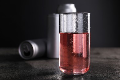 Energy drink in glass and aluminium cans on grey table, closeup. Space for text