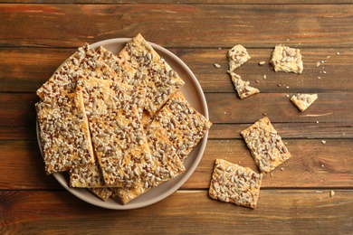 Photo of Delicious crispy crackers on wooden table, flat lay
