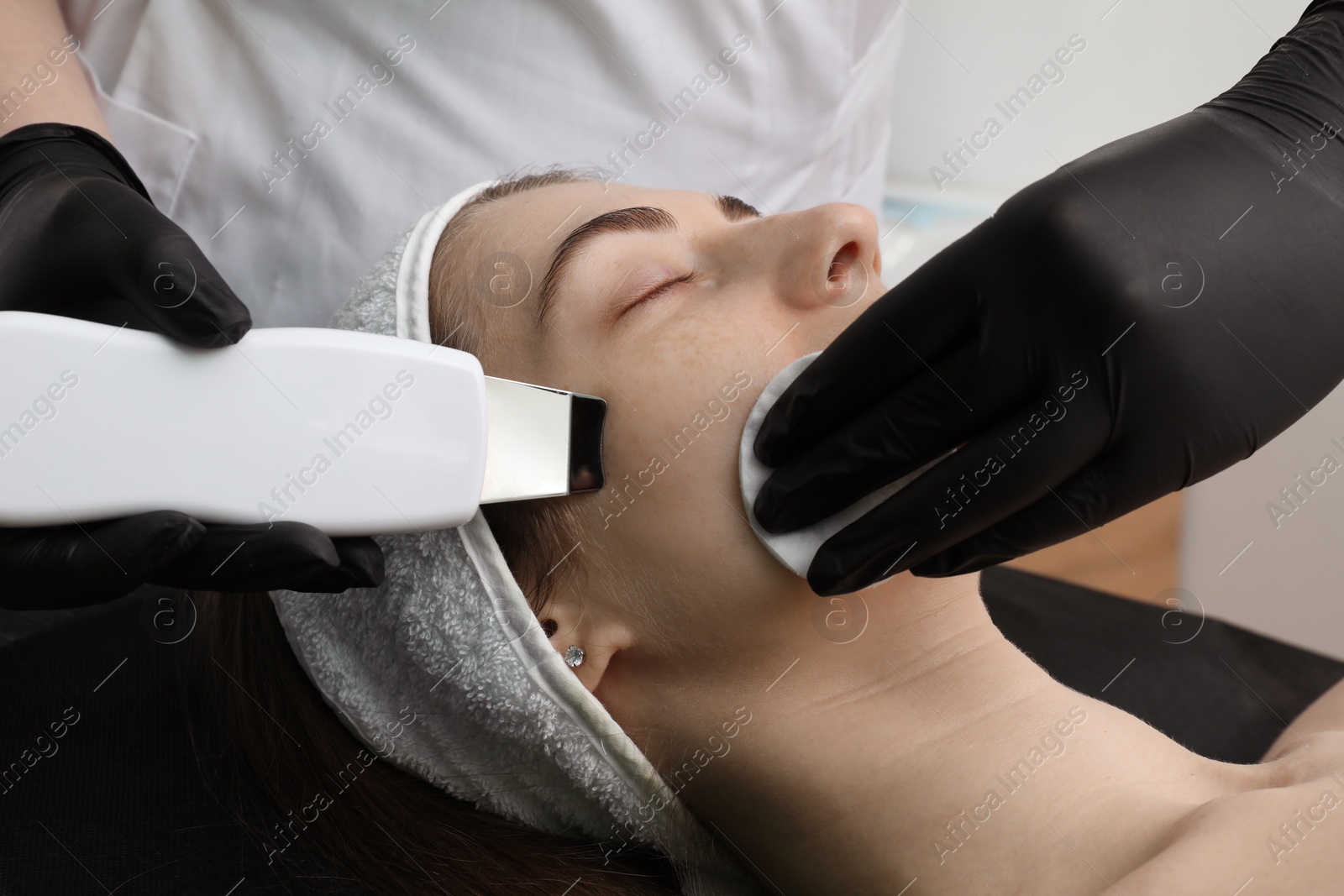 Photo of Cosmetologist using ultrasonic scrubber, closeup. Client having cleansing procedure indoors