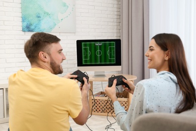 Happy young couple playing video games at home