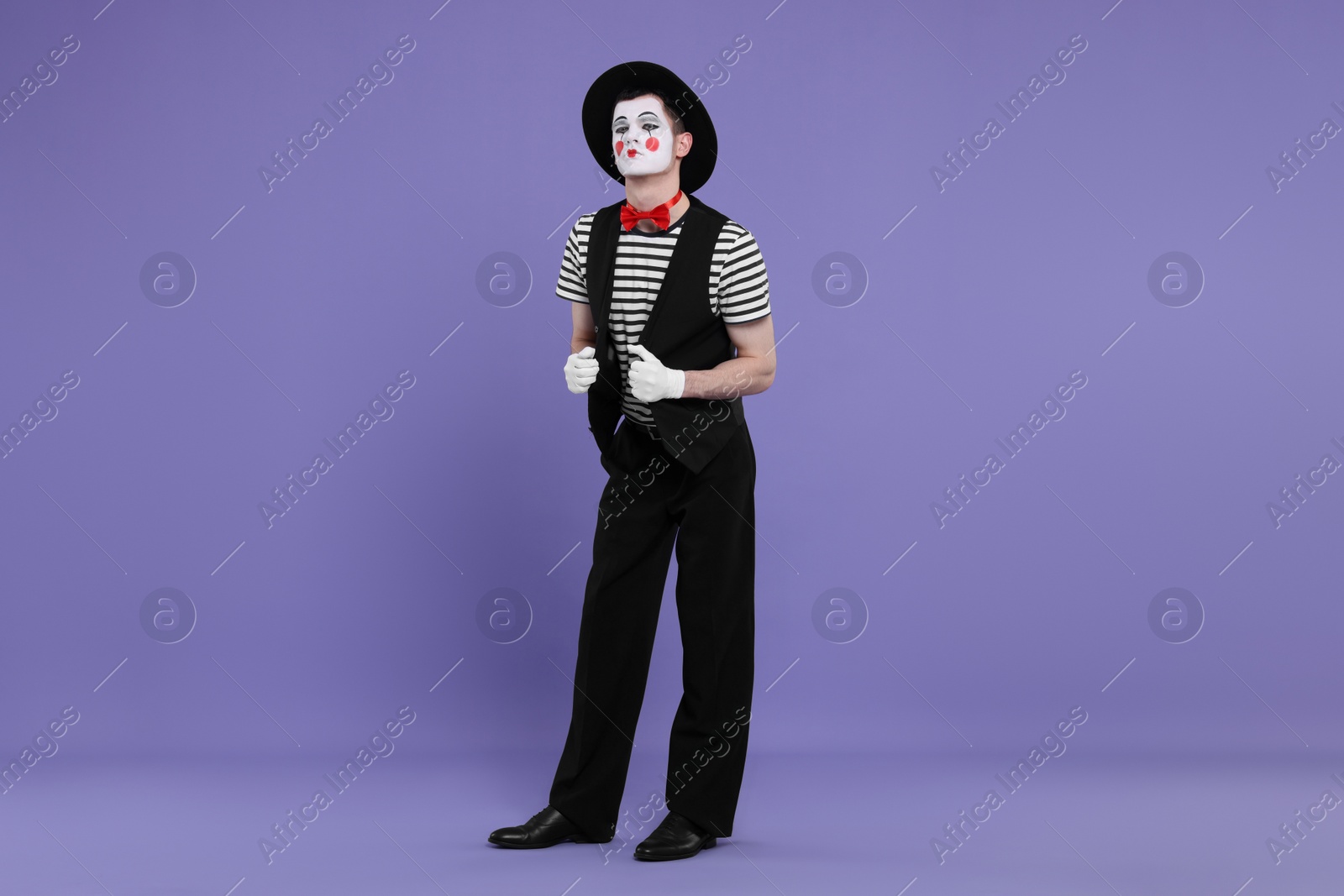 Photo of Funny mime artist in hat posing on purple background